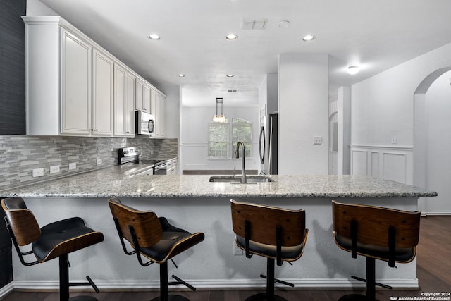 kitchen featuring kitchen peninsula, decorative light fixtures, sink, appliances with stainless steel finishes, and a breakfast bar area