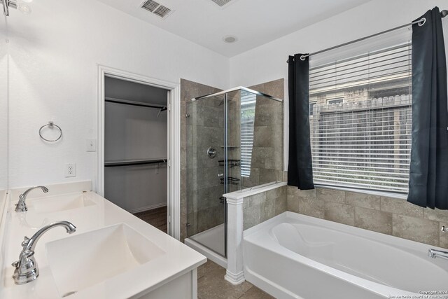 bathroom featuring tile flooring, double sink, and plus walk in shower