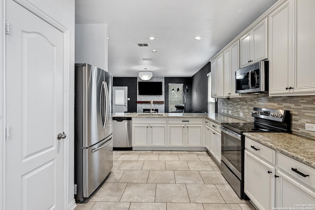 kitchen with appliances with stainless steel finishes, backsplash, sink, white cabinetry, and kitchen peninsula