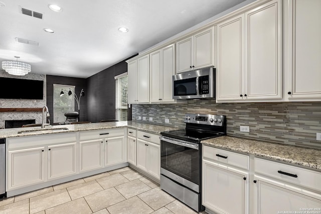 kitchen with stainless steel appliances, backsplash, light stone counters, and sink