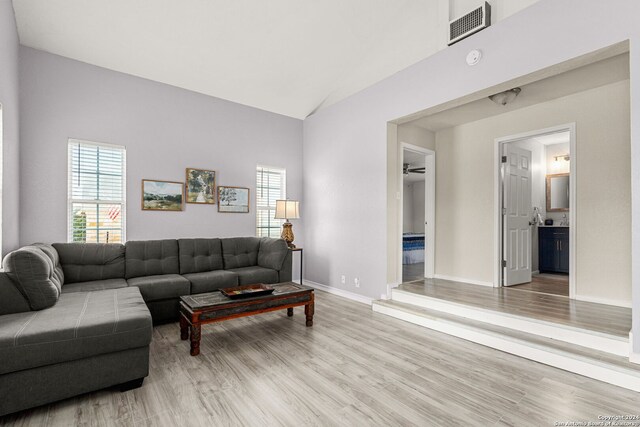 living room with light hardwood / wood-style floors and high vaulted ceiling