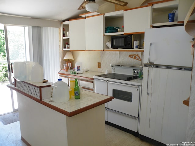 kitchen featuring a healthy amount of sunlight, light tile flooring, white appliances, and white cabinetry