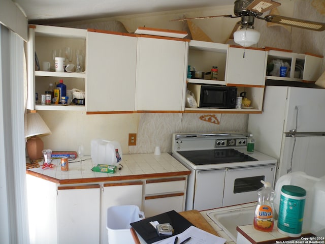 kitchen featuring double oven range, white cabinetry, ceiling fan, and tile countertops