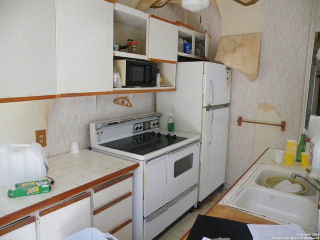 kitchen with sink, white cabinets, range with two ovens, and tile countertops