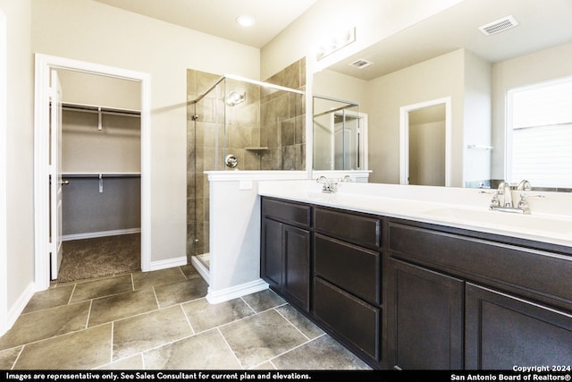 bathroom with a shower with shower door, double vanity, and tile floors