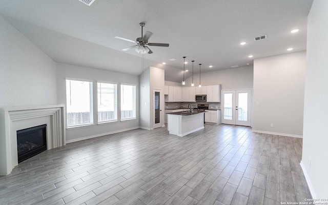 kitchen featuring ceiling fan, white cabinets, a center island with sink, french doors, and light wood-type flooring