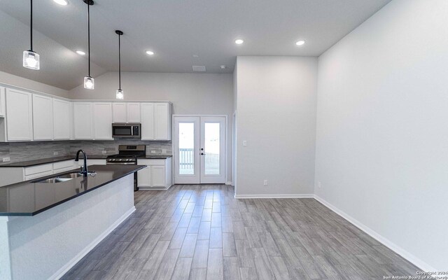 kitchen with sink, appliances with stainless steel finishes, pendant lighting, decorative backsplash, and white cabinets