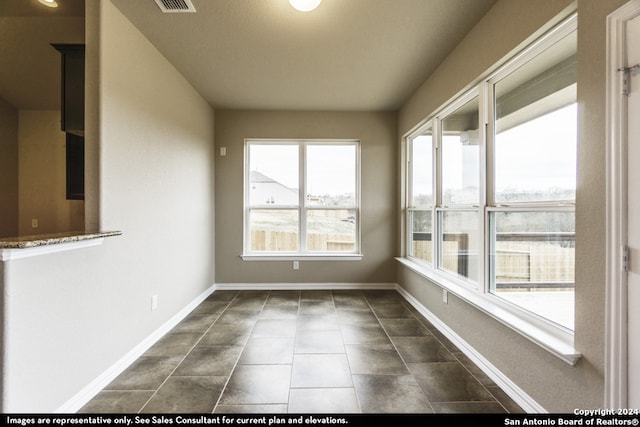 empty room with a wealth of natural light and dark tile floors