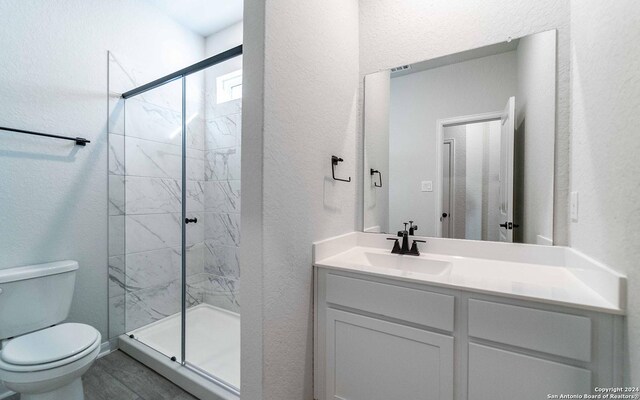 bathroom with walk in shower, vanity, and toilet