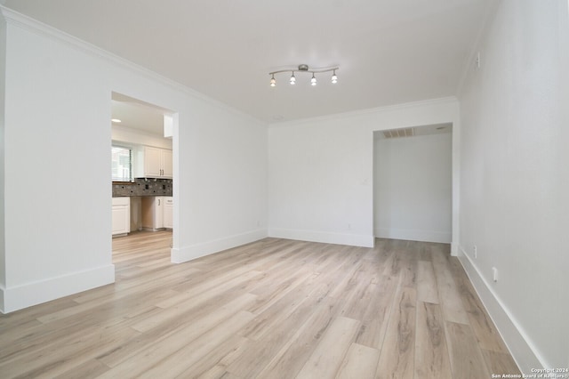 spare room with ornamental molding and light hardwood / wood-style flooring