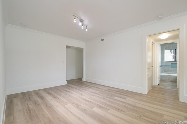 spare room featuring crown molding and light hardwood / wood-style floors