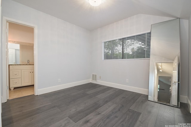 unfurnished bedroom with dark hardwood / wood-style floors, lofted ceiling, sink, and ensuite bath