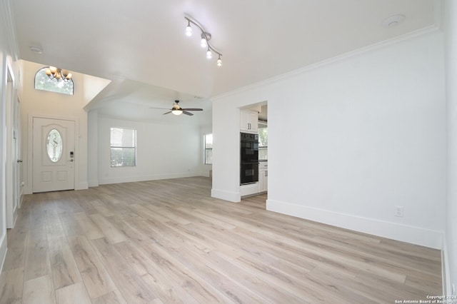 unfurnished living room with ceiling fan with notable chandelier, light hardwood / wood-style flooring, and ornamental molding