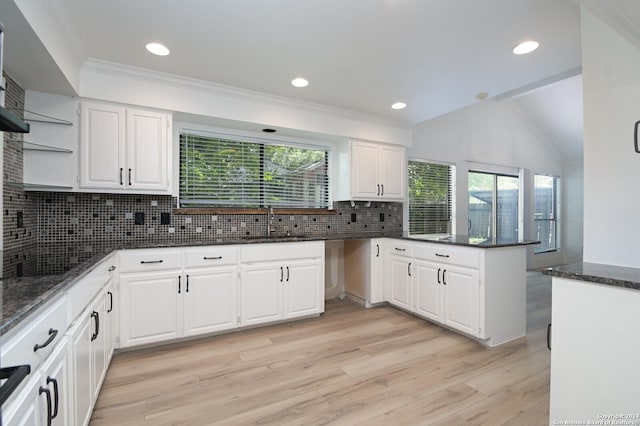 kitchen featuring sink, backsplash, kitchen peninsula, light hardwood / wood-style floors, and white cabinets