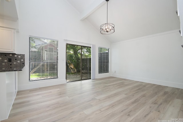 unfurnished living room with beamed ceiling, a chandelier, and light hardwood / wood-style floors