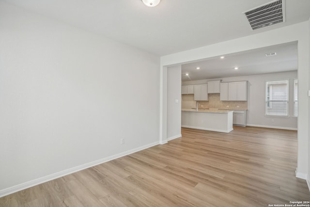 unfurnished living room featuring light hardwood / wood-style floors and sink