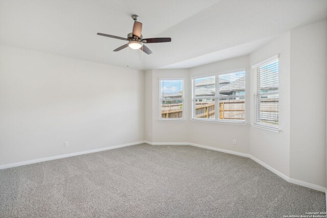 carpeted spare room featuring ceiling fan and plenty of natural light