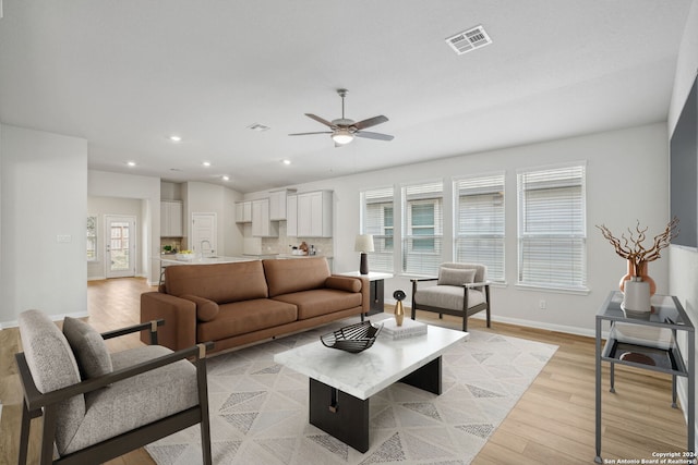 living room featuring ceiling fan, light hardwood / wood-style flooring, and sink