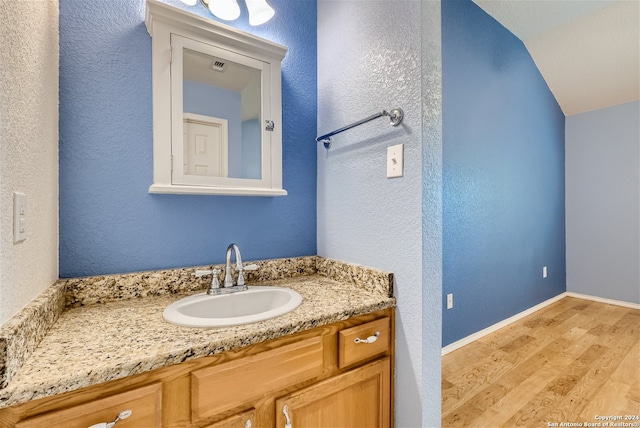 bathroom featuring vanity, lofted ceiling, and wood-type flooring