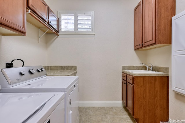 laundry room with washing machine and clothes dryer, sink, light tile patterned floors, and cabinets