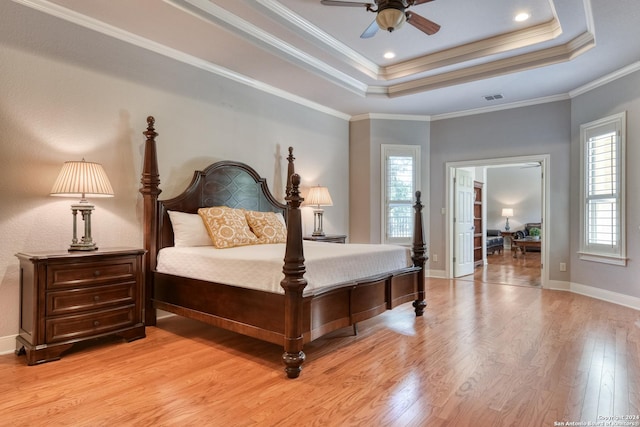 bedroom with ceiling fan, multiple windows, crown molding, and a tray ceiling