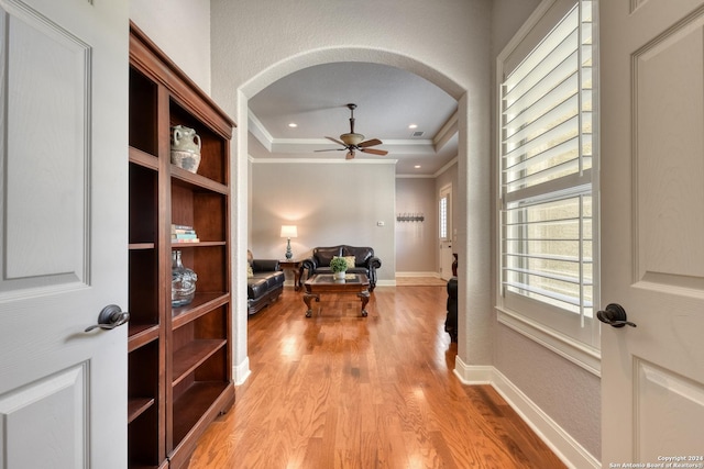 hallway with light wood-type flooring and ornamental molding