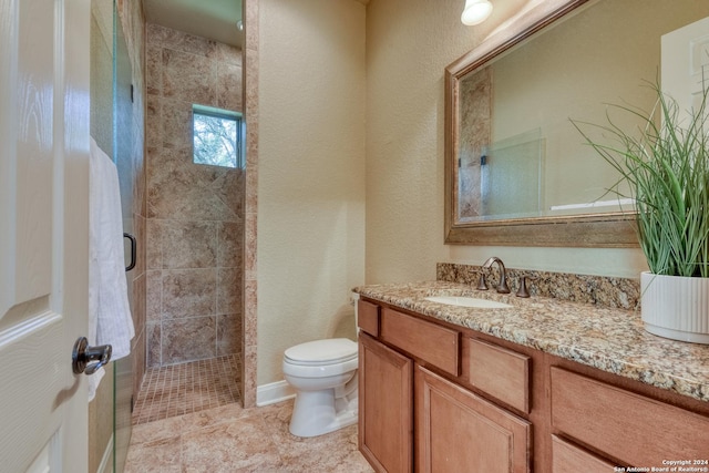 bathroom featuring a tile shower, vanity, and toilet