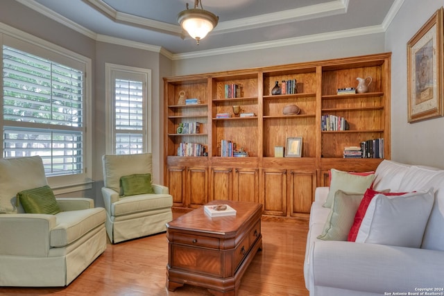 sitting room featuring light hardwood / wood-style floors, a raised ceiling, and ornamental molding