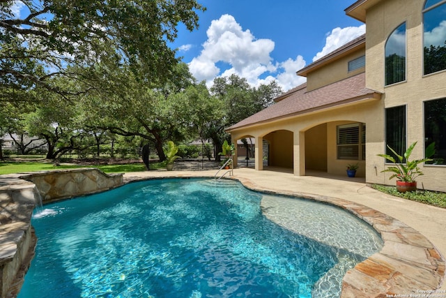 view of swimming pool with pool water feature and a patio