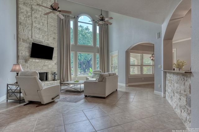 tiled living room featuring ceiling fan and a fireplace