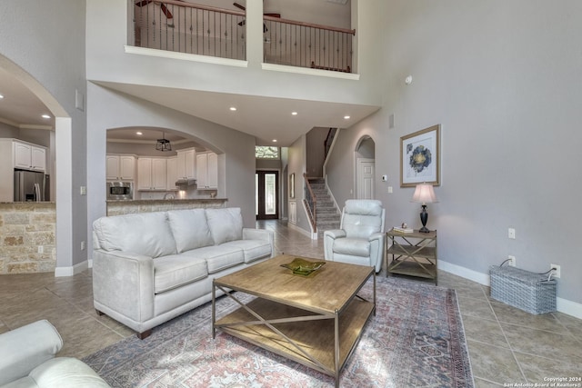 living room featuring ceiling fan, a towering ceiling, and light tile patterned floors