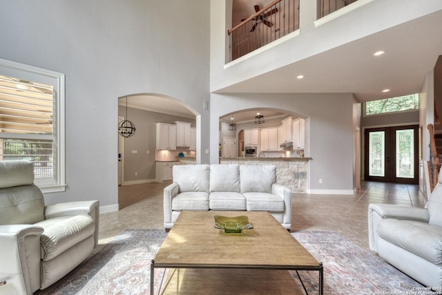 tiled living room featuring a wealth of natural light, french doors, and a high ceiling