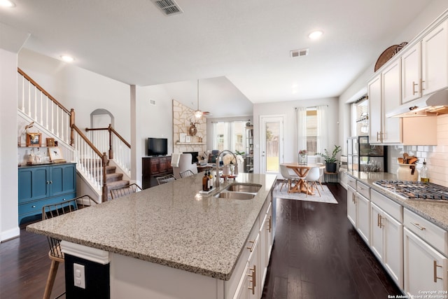 kitchen featuring a kitchen breakfast bar, sink, a fireplace, an island with sink, and white cabinetry