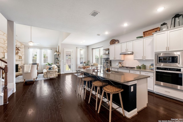 kitchen featuring appliances with stainless steel finishes, ceiling fan, a kitchen island with sink, sink, and white cabinets