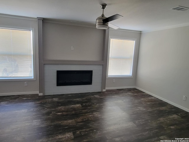 unfurnished living room featuring ceiling fan, a large fireplace, dark hardwood / wood-style flooring, and ornamental molding