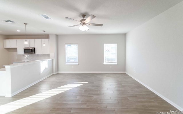3569 Alto Stratus, New Braunfels, TX 78130 - unfurnished living room featuring baseboards, visible vents, a ceiling fan, and light wood-style flooring