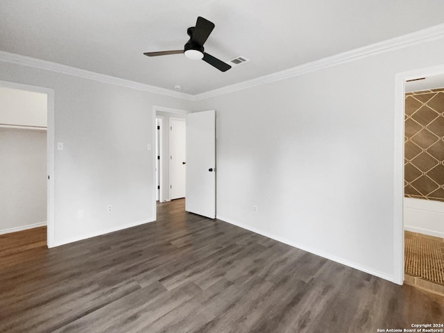 unfurnished bedroom featuring crown molding, a spacious closet, dark hardwood / wood-style floors, and a closet