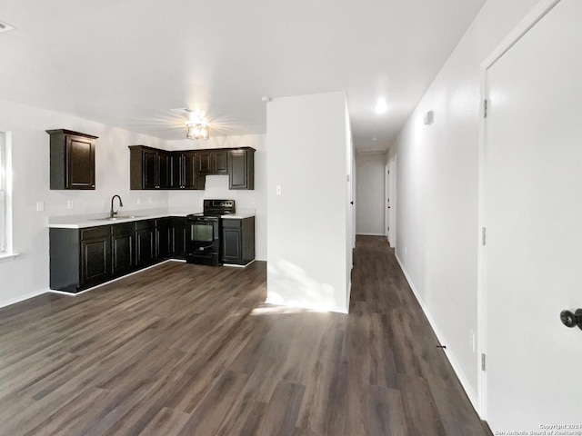 kitchen with black range with electric cooktop, dark hardwood / wood-style floors, dark brown cabinets, and sink