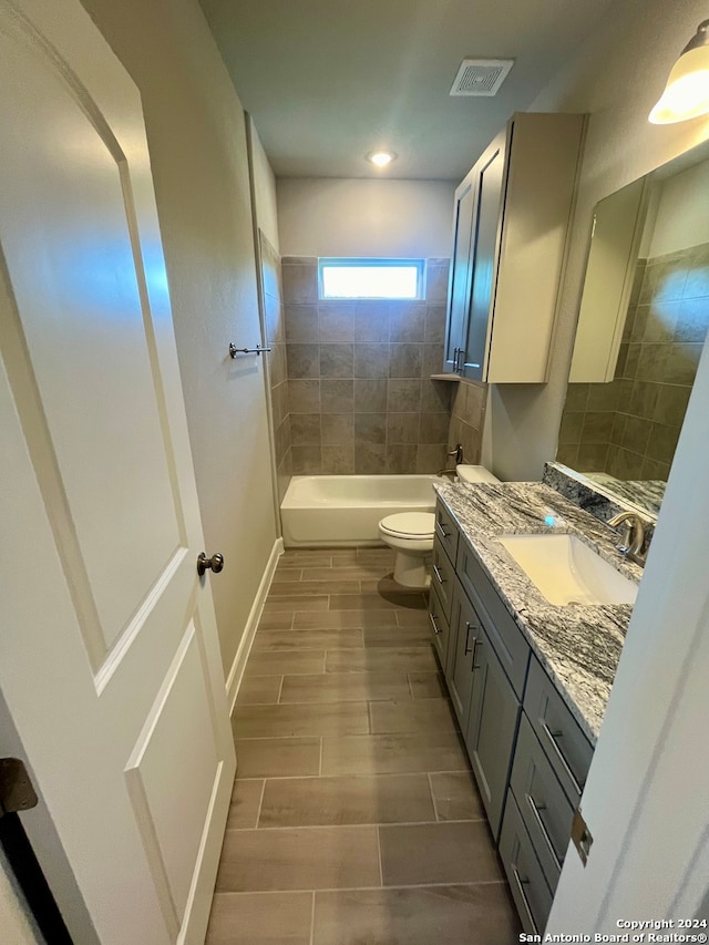 full bathroom featuring tile floors, vanity, toilet, and tiled shower / bath combo