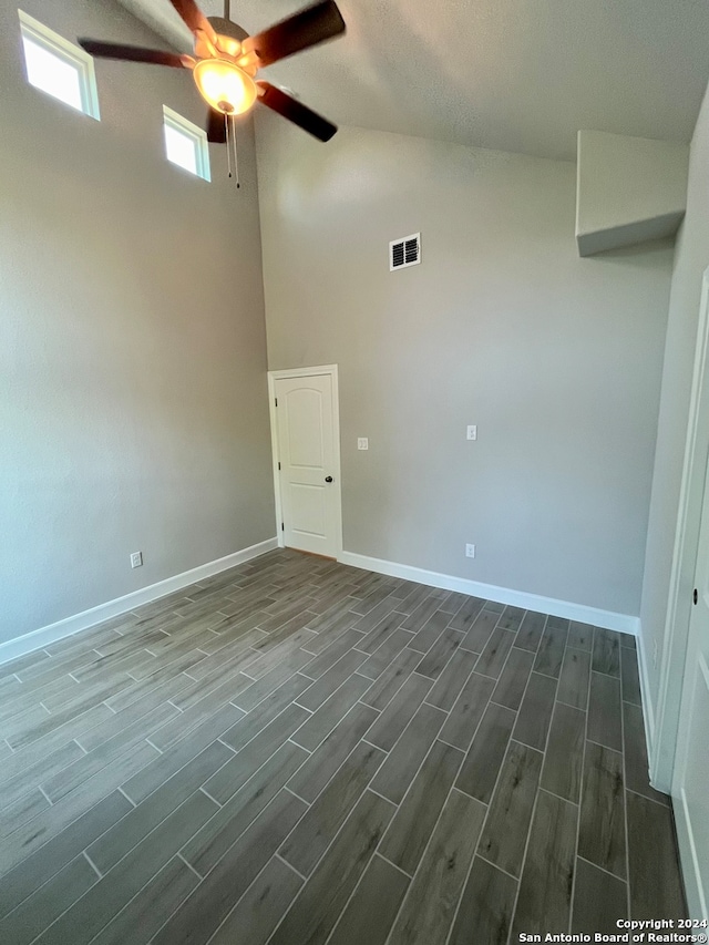 empty room with high vaulted ceiling, ceiling fan, and hardwood / wood-style flooring