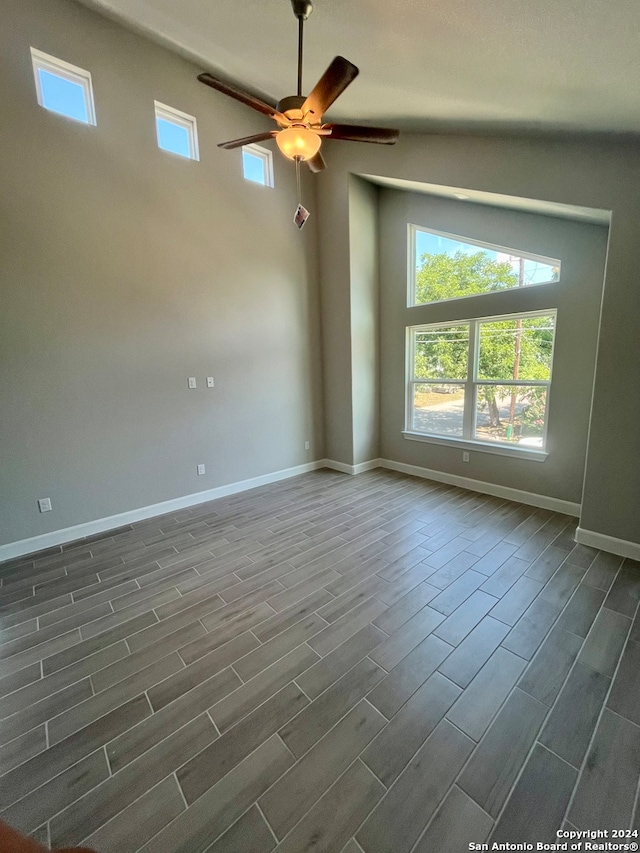 unfurnished room with a towering ceiling, a wealth of natural light, dark hardwood / wood-style floors, and ceiling fan