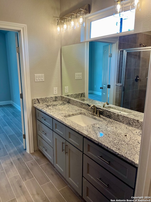 bathroom featuring a shower with shower door and vanity