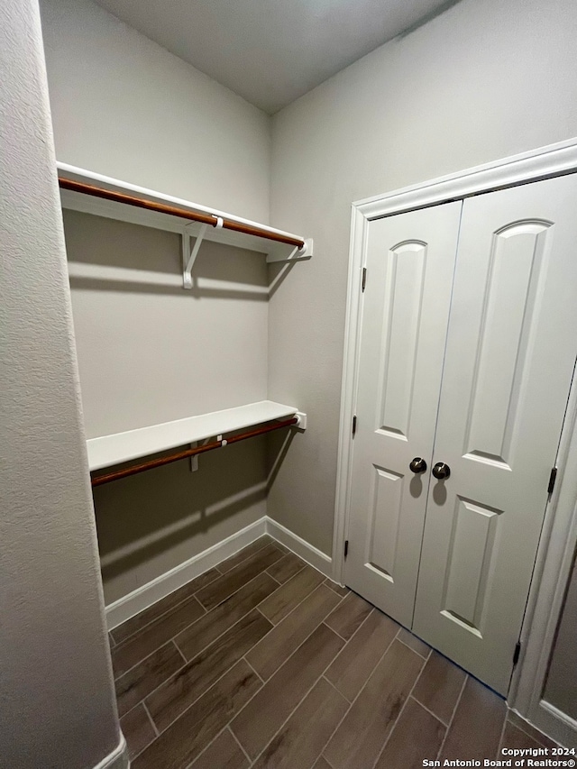 walk in closet with dark hardwood / wood-style floors