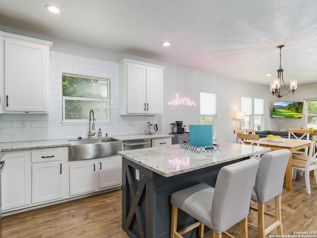 kitchen with sink, white cabinetry, tasteful backsplash, pendant lighting, and light stone countertops