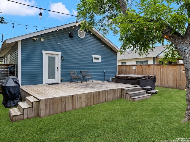 rear view of property with a lawn, a covered hot tub, and a deck