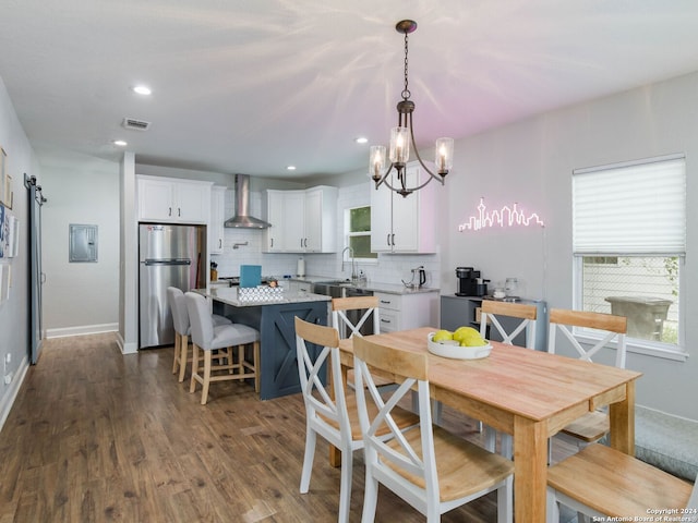 dining room with sink, dark wood-type flooring, electric panel, and a barn door