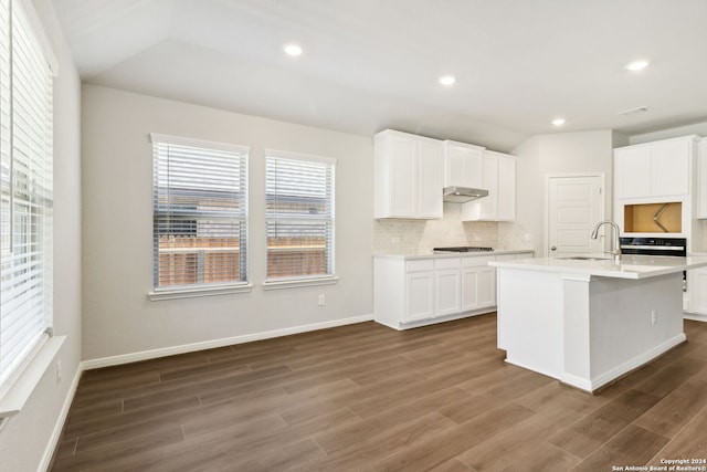 kitchen featuring light countertops, an island with sink, a sink, and white cabinets