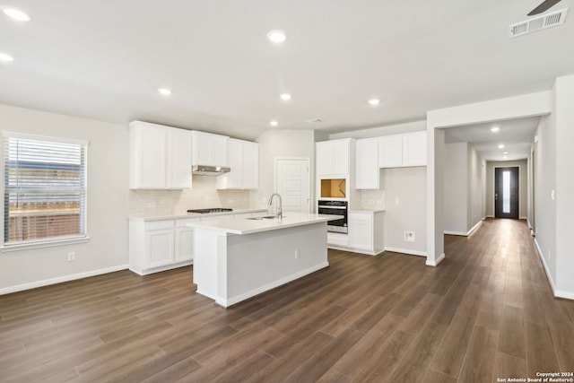 kitchen featuring visible vents, an island with sink, oven, light countertops, and a sink