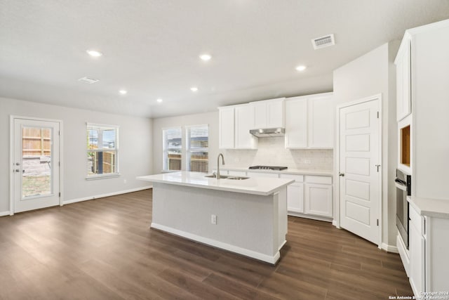 kitchen featuring a sink, visible vents, white cabinets, light countertops, and a center island with sink