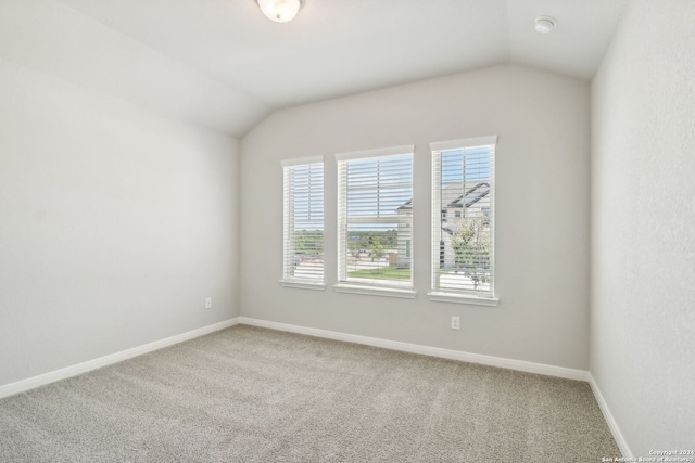 carpeted spare room with lofted ceiling and baseboards